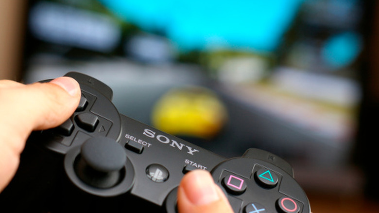 A close-up of a person holding a PlayStation 3 controller.