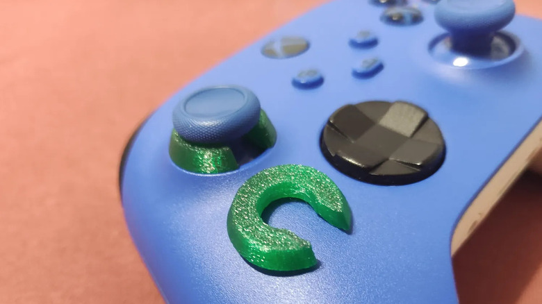 Xbox controller with a green 3D-printed stick protector around the thumbstick.