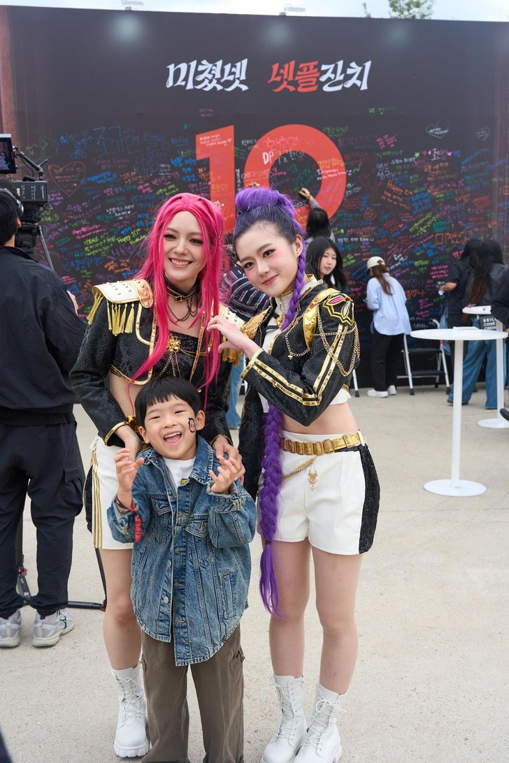 A fan poses with cosplayers dressed as members of Huntrix from 'KPop Demon Hunters' (2025) at the Netflix Janchi fan event in Seoul, Saturday. Courtesy of Netflix