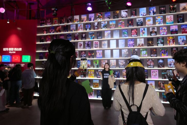 Fans take photos in front of a wall featuring a list of Netflix titles during the Netflix Janchi event at Oil Tank Culture Park in Mapo District, western Seoul, Sunday. Courtesy of Netflix