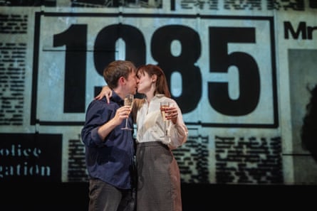 In a scene from Our Friends in the North, a couple kisses holding champagne glasses before a ‘1985’ backdrop