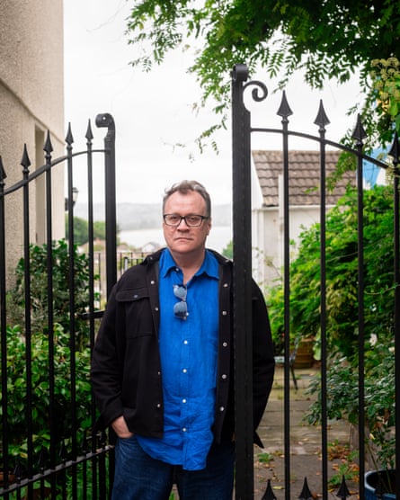 Davies photographed in front of metal gates with lots of foliage around