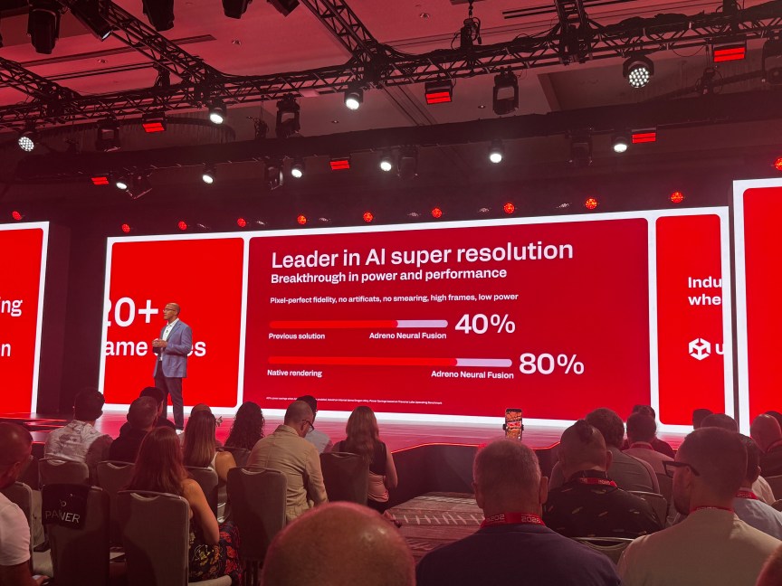 A man stands on stage in front of a screen showing performance gains from last year's chips.