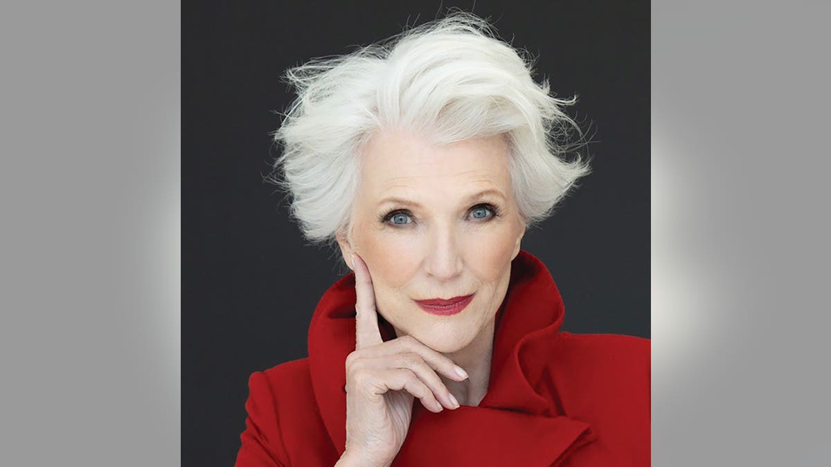 Maye Musk posing in a bright red suit.
