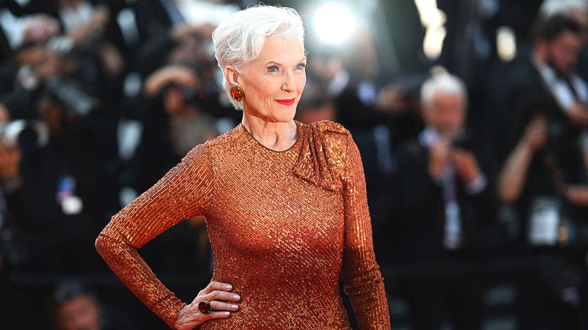 Maye Musk in a sparkling orange dress posing for the cameras.