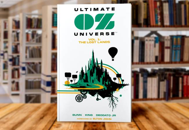 Book cover for Ultimate OZ Universe Vol. 1: The Lost Lands by AWA Studios, featuring a graphic illustration of a dark fantasy castle and a hot air balloon, sitting on a wooden table in front of blurred bookshelves.