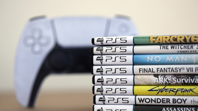 stack of PS5 games with playstation 5 controller blurred in background
