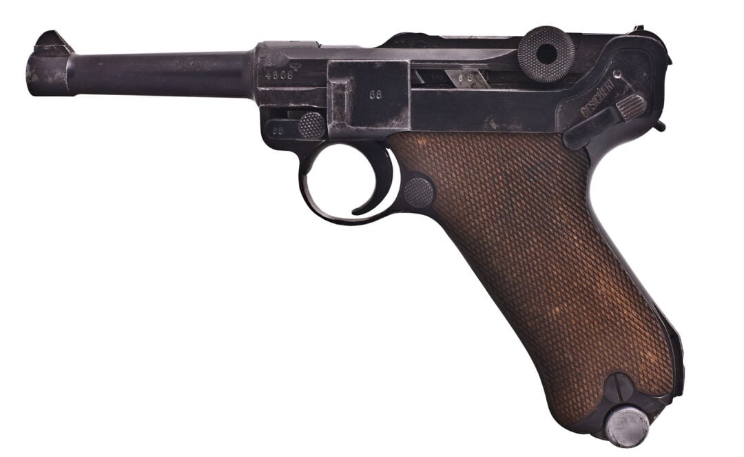 A vintage pistol with a dark metal frame and brown textured grip, featuring a distinctive toggle-lock mechanism and rounded barrel, isolated on a white background.