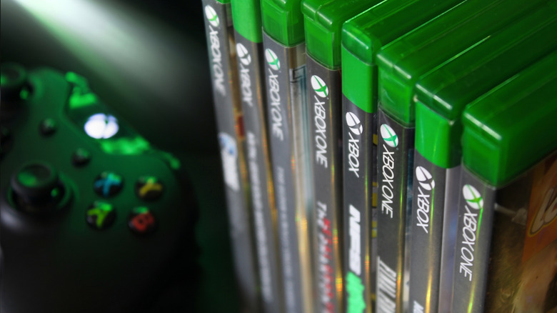 Xbox One CDs on a shelf next to a controller