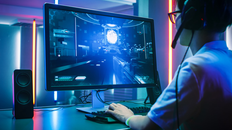 A gamer playing a first-person shooter on a monitor.