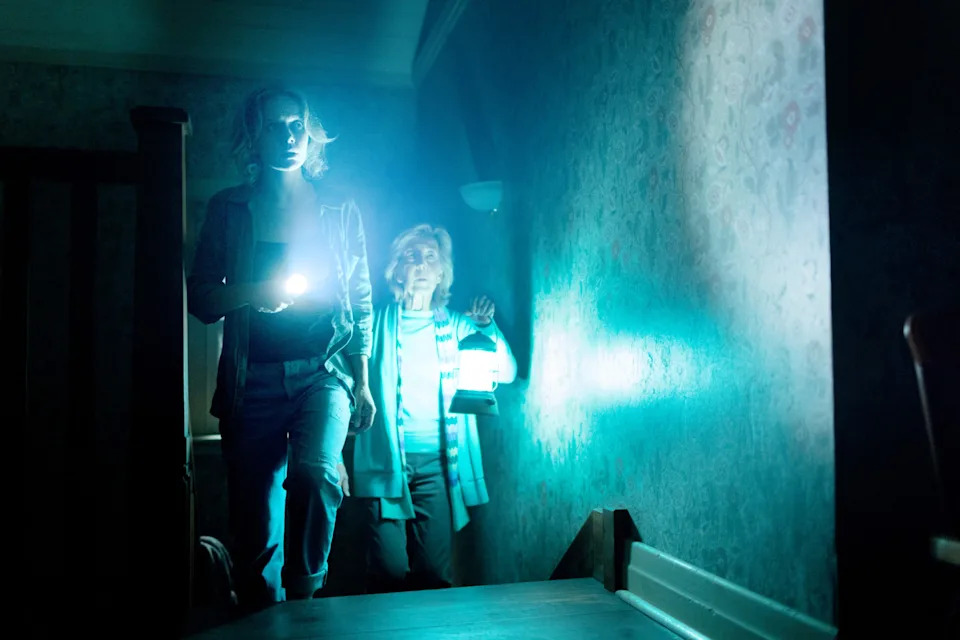 Amelia Eve and Lin Shaye in Insidious: Out of the Further. Two women hold a flashlight and a lantern as they explore a house.