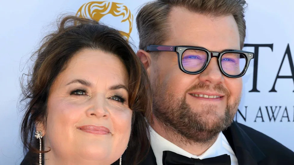 James Corden and Ruth Jones smiling at an award event, dressed in formal attire.