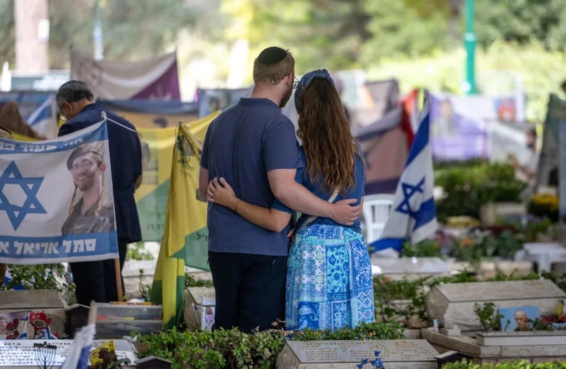 A couple embrace at the Mt Herzl military cemetery, at the section with victims killed in the October 7 Hamas attack, October 05, 2026. (credit: CHAIM GOLDBERG/FLASH90)