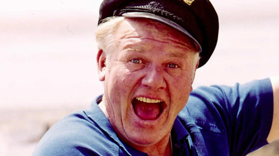 Skipper smiles enthusiastically while holding up an unseen fish