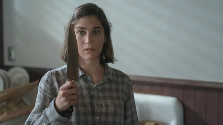 Annie Wilkes holding a knife and looking at it