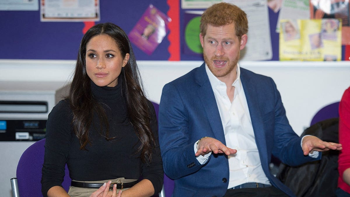 Prince Harry and Meghan Markle gesture during a visit to Nottingham Academy.