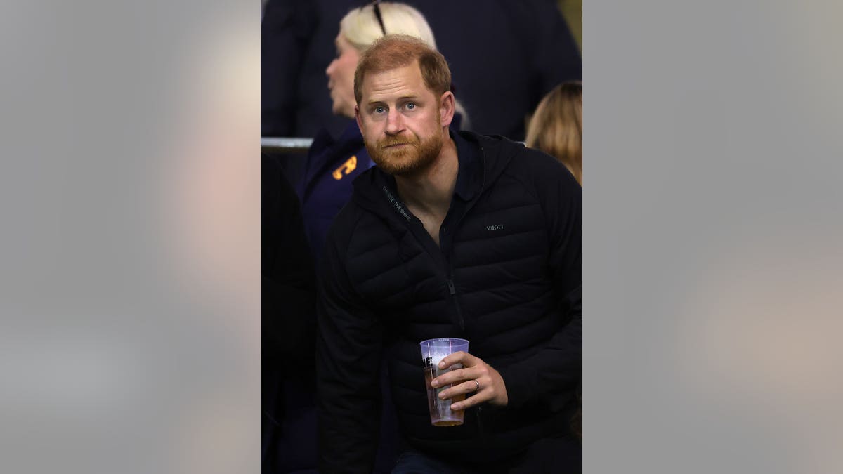 Prince Harry, Duke of Sussex, sits in the stands during a rugby match.