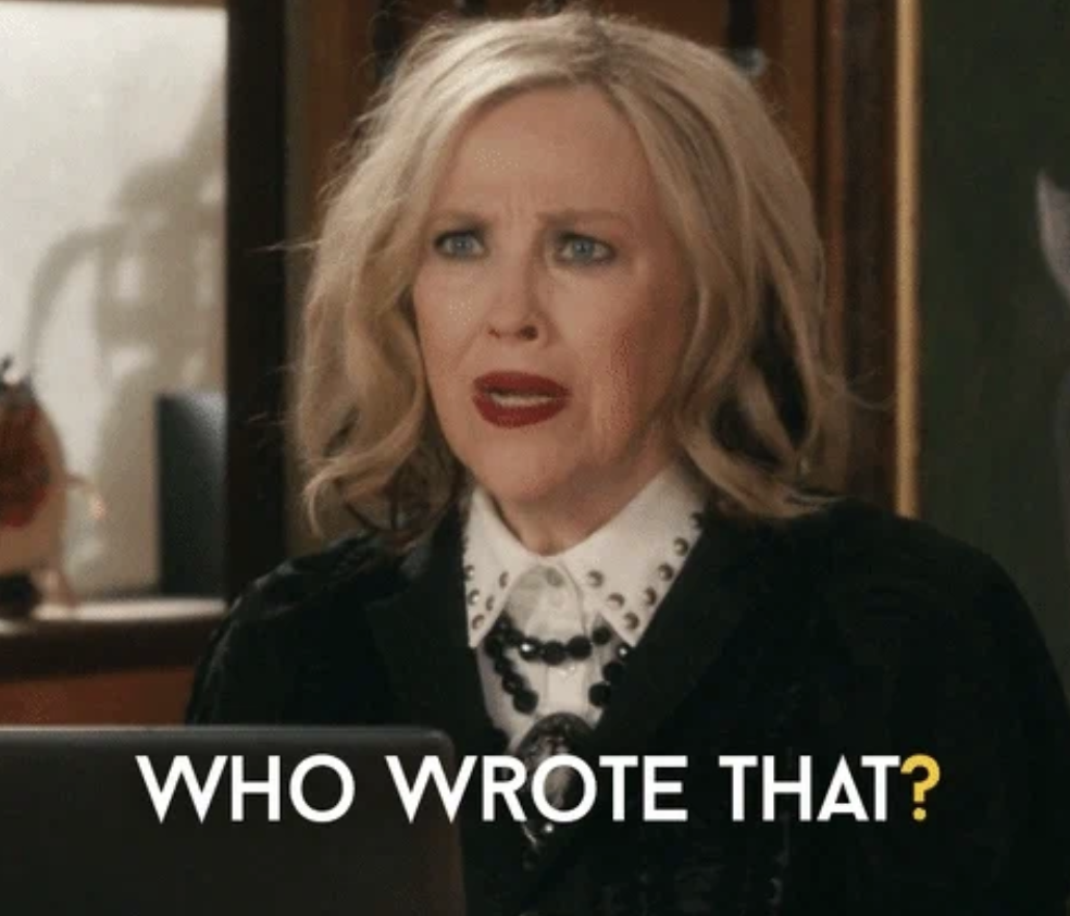 Actor with surprised expression, wearing a black outfit with white accents, asks, "Who wrote that?" in bold white text