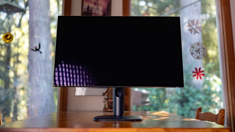 The Alienware AW3226Q powered off on a table in front of windows.