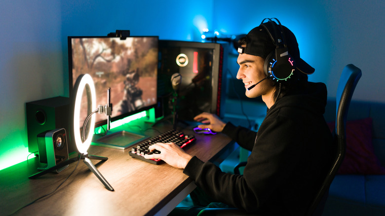 A young man playing a first-person shooter on a gaming PC.