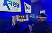 A man wearing a virtual reality headset holds two controllers at a computer station in ODU’s virtual reality lab.