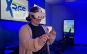 A smiling woman wearing a virtual reality headset reaches forward with both hands in ODU’s virtual reality lab.
